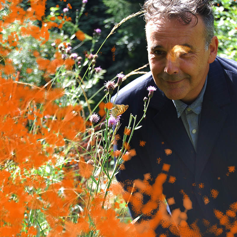 Photo of Rob Newman standing outside behind a big group of wild flowers