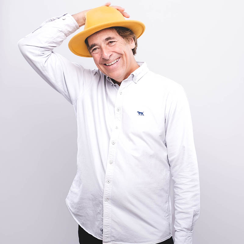 Photo of Mark Steel smiling and wearing a yellow hat