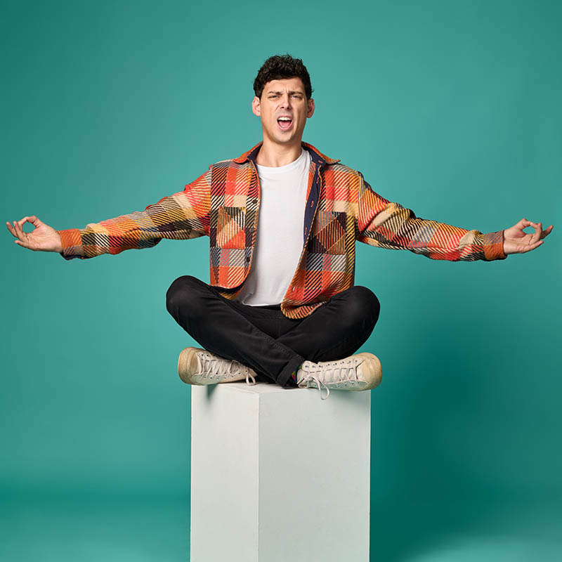 Photo of Matt Richardson sat on a plinth in a yoga pose