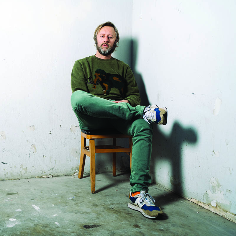 Photo of Rory Scovel sat on a chair in the corner of a room